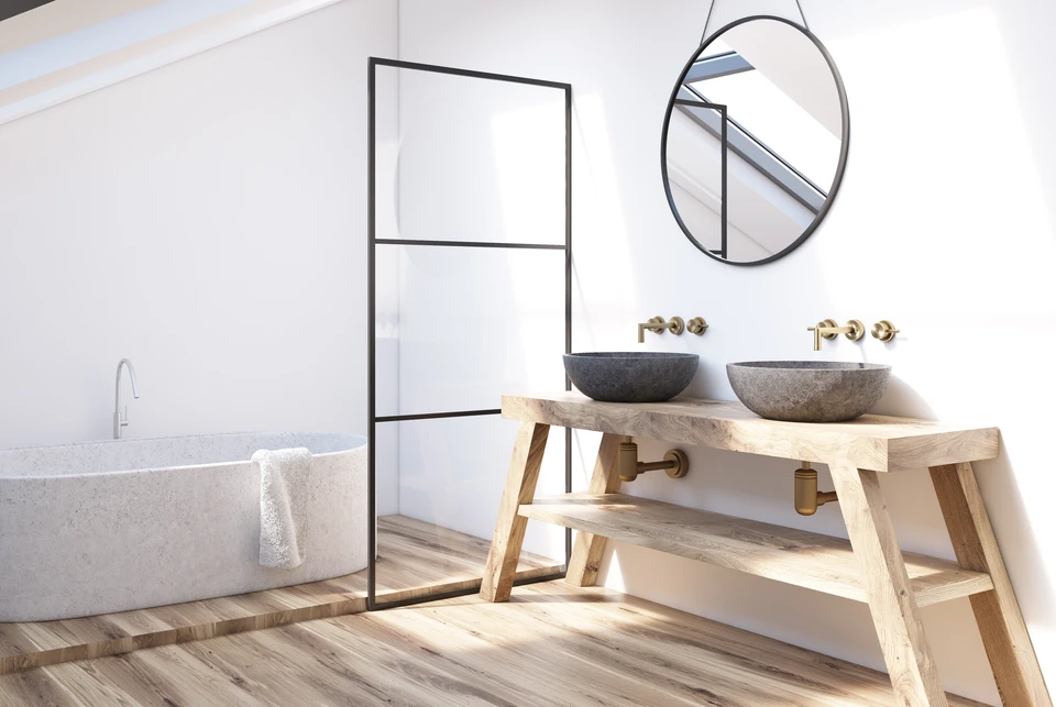 Intérieur moderne de la salle de bains avec une tablette en bois, deux lavabos, un miroir rond et une baignoire